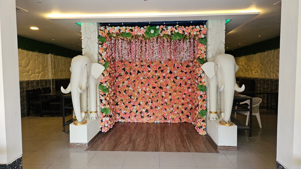 A wall of peach, pink and cream roses framed by two white elephant statues on plinths at Rasa Raya